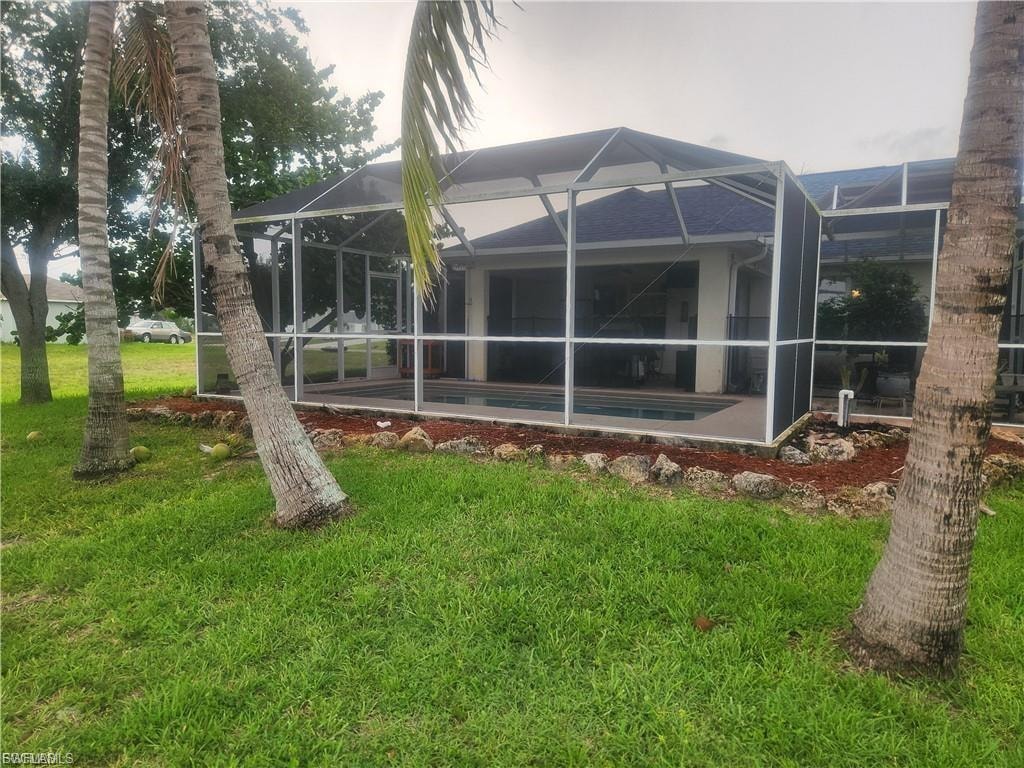 Rear view of property with a pool, a lawn, a lanai, and a sunroom