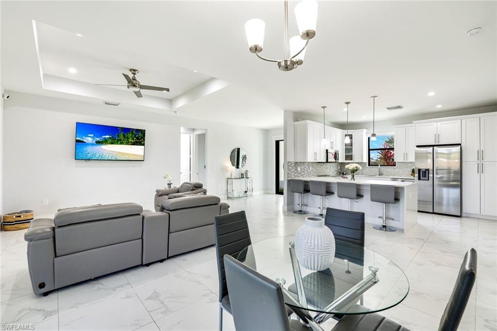 Dining space with a ceiling fan, light marble finish flooring, and suspended lighting