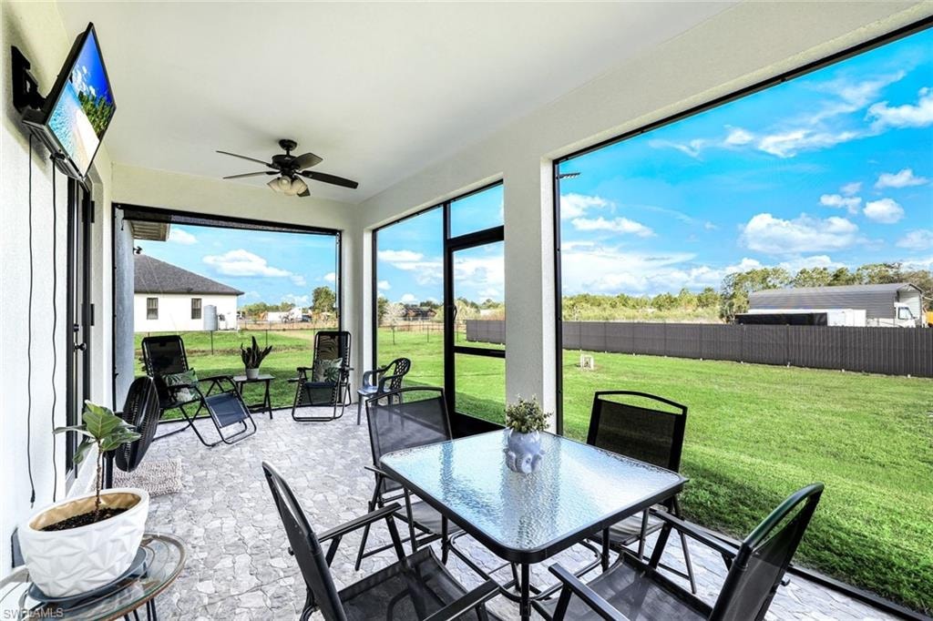 Sunroom with a ceiling fan, outdoor dining area, and a patio