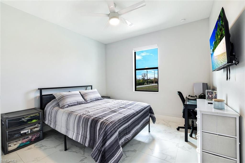 Bedroom with light marble finish flooring, a ceiling fan, and an office area