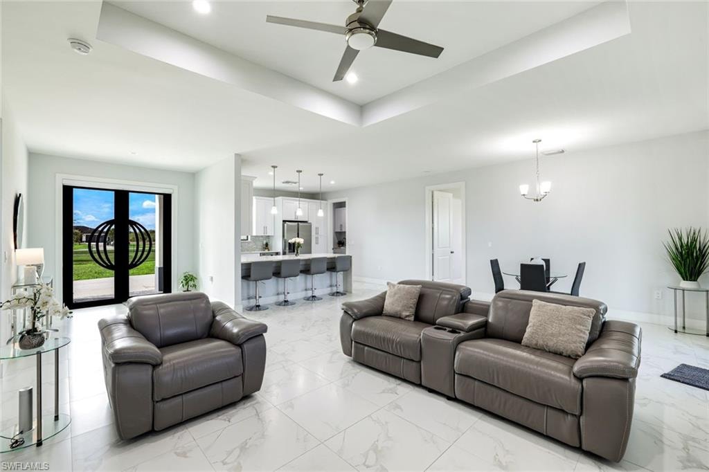 Living area with a chandelier, ceiling fan, and a raised ceiling