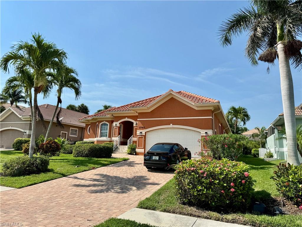 Mediterranean / spanish-style house with an attached garage, stucco siding, a tiled roof, driveway, and a front yard
