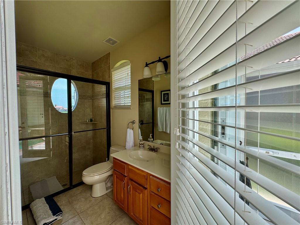 Bathroom with a shower stall, vanity, and light tile patterned flooring