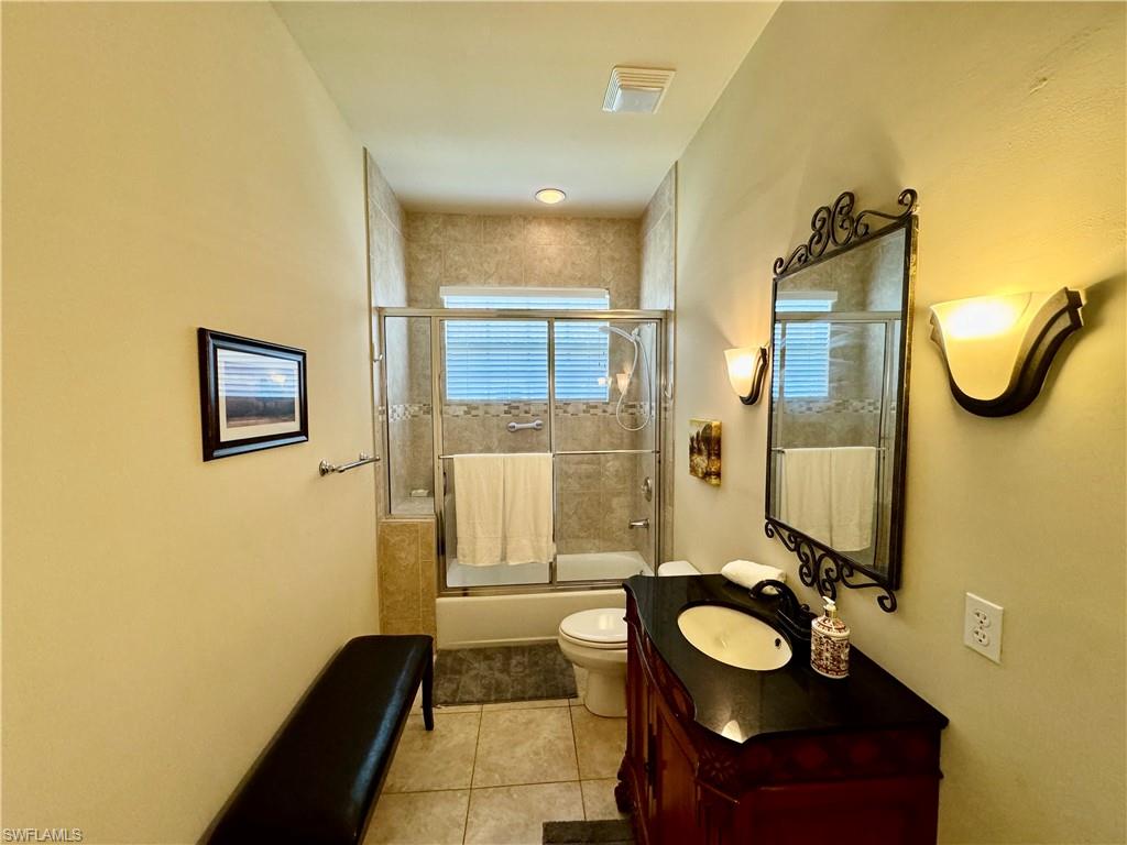 Full bath featuring vanity, combined bath / shower with glass door, and light tile patterned floors