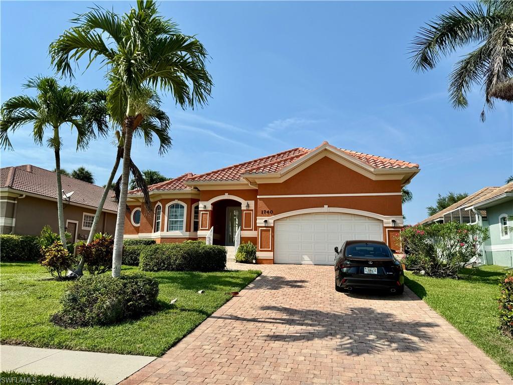 Mediterranean / spanish-style house with a front lawn, an attached garage, decorative driveway, and stucco siding