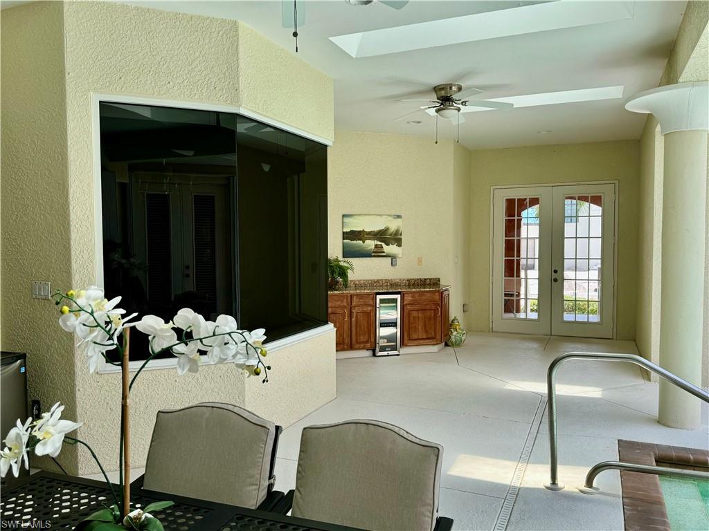 Dining area featuring a ceiling fan, french doors, a skylight, wine cooler, and a textured wall
