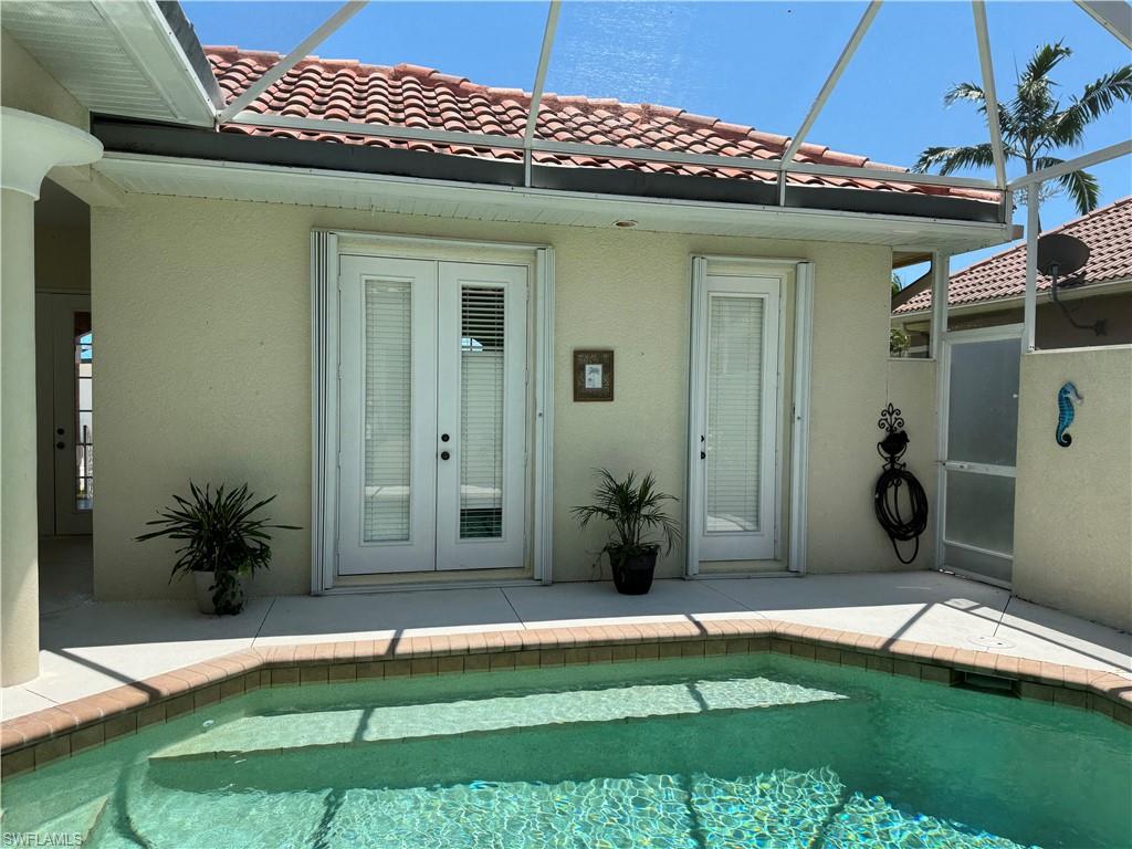 Rear view of house with an outdoor pool, stucco siding, a patio, and french doors