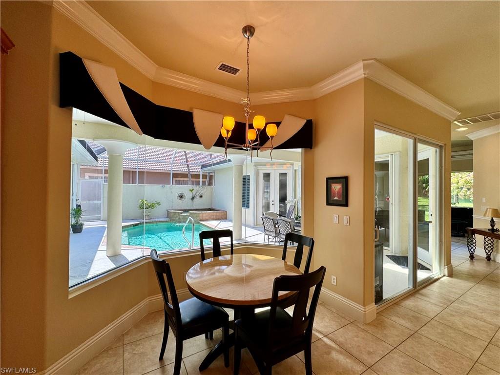 Dining area with crown molding, a chandelier, light tile patterned floors, and a sunroom