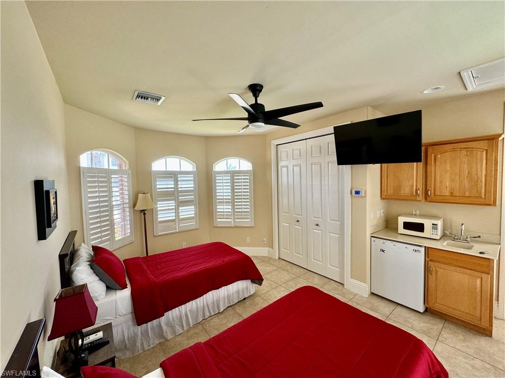 Bedroom with a ceiling fan, light tile patterned floors, and a closet