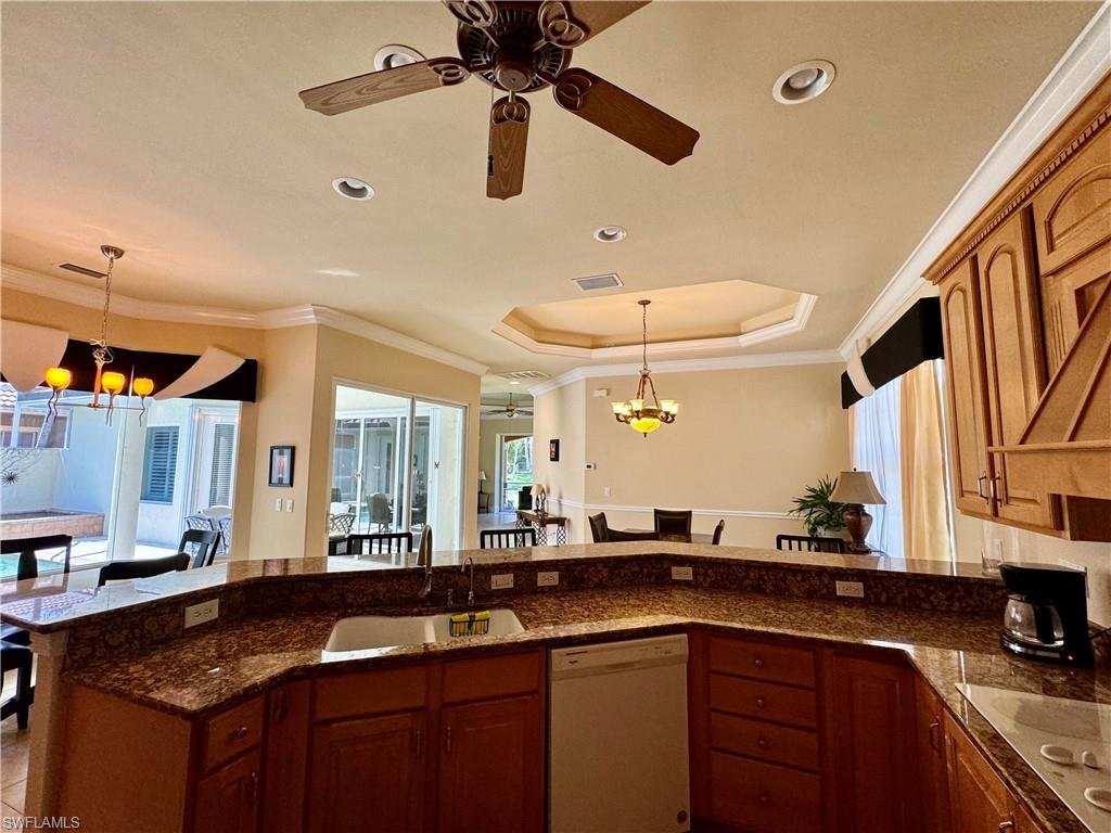 Kitchen featuring suspended lighting, ceiling fan, wood finish cabinetry, white appliances, and ornamental molding