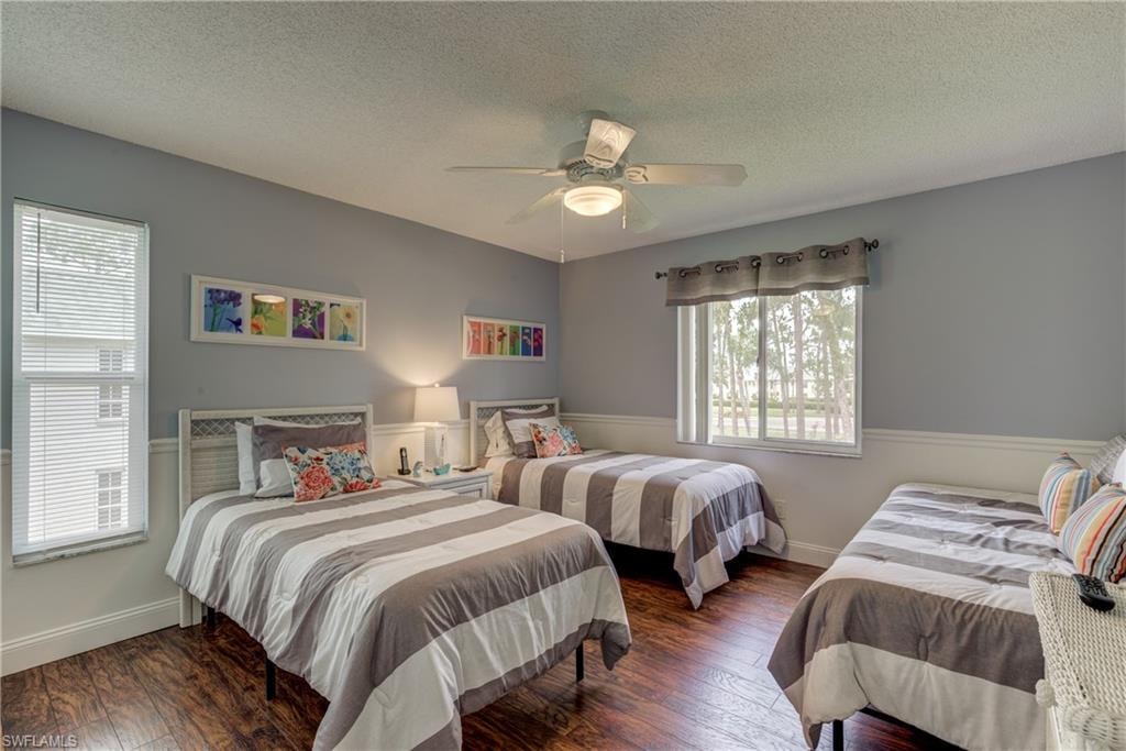 Bedroom featuring dark wood-style flooring, a textured ceiling, and a ceiling fan