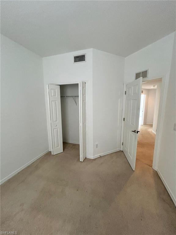Unfurnished bedroom featuring light carpet and a closet