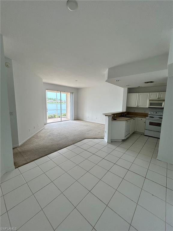 Unfurnished living room featuring light tile patterned flooring and a water view