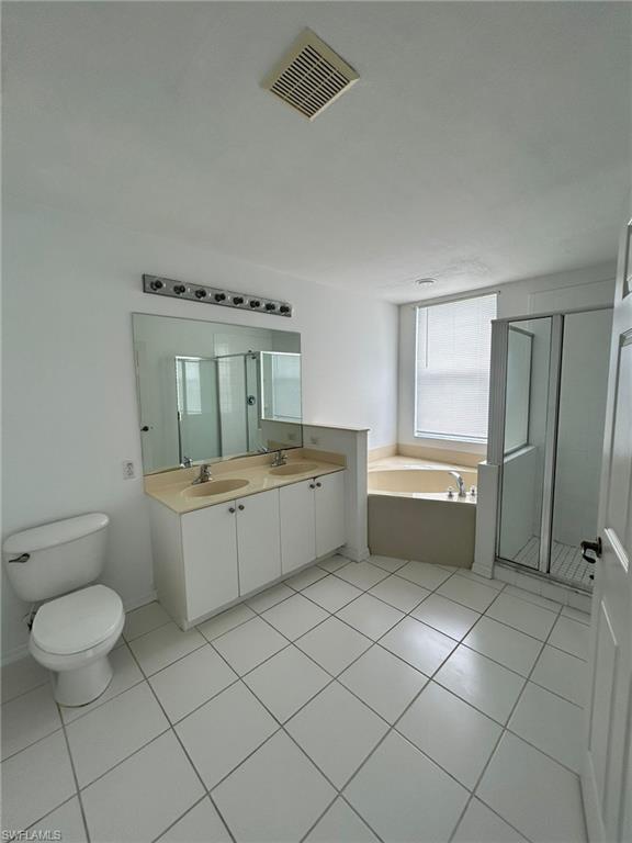 Full bathroom featuring light tile patterned floors, a stall shower, a bath, and double vanity