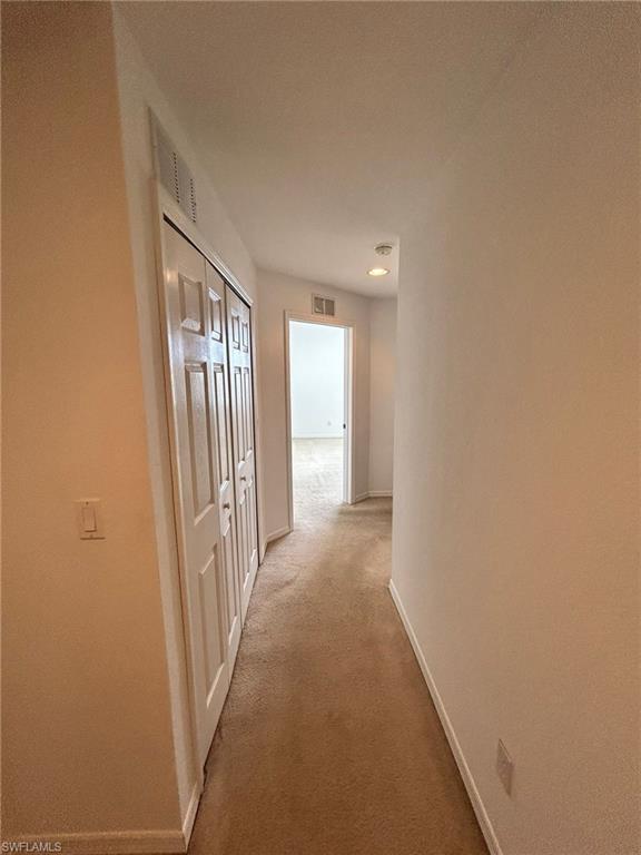 Corridor with carpet flooring and baseboards