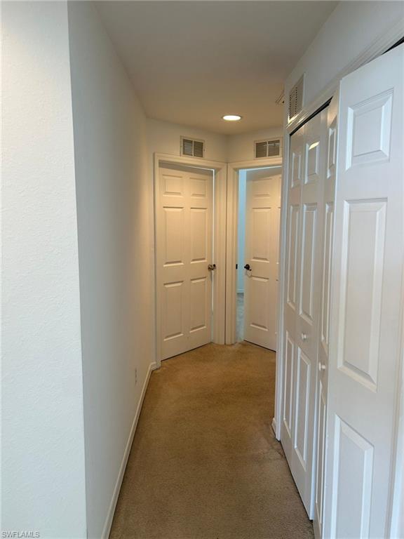 Hallway with light colored carpet and baseboards