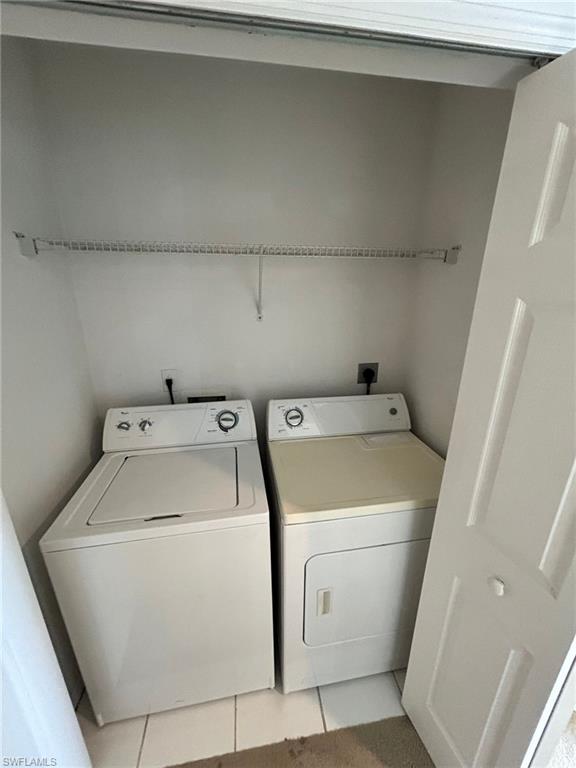 Laundry area with light tile patterned floors and separate washer and dryer