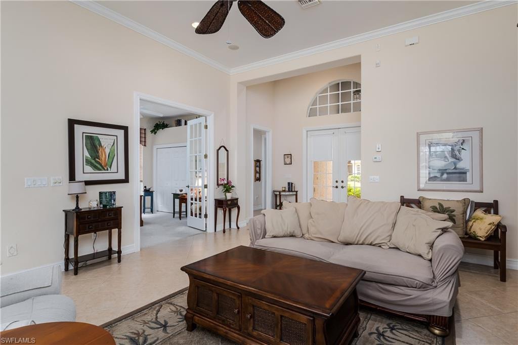 Living area with french doors, a ceiling fan, ornamental molding, and a high ceiling
