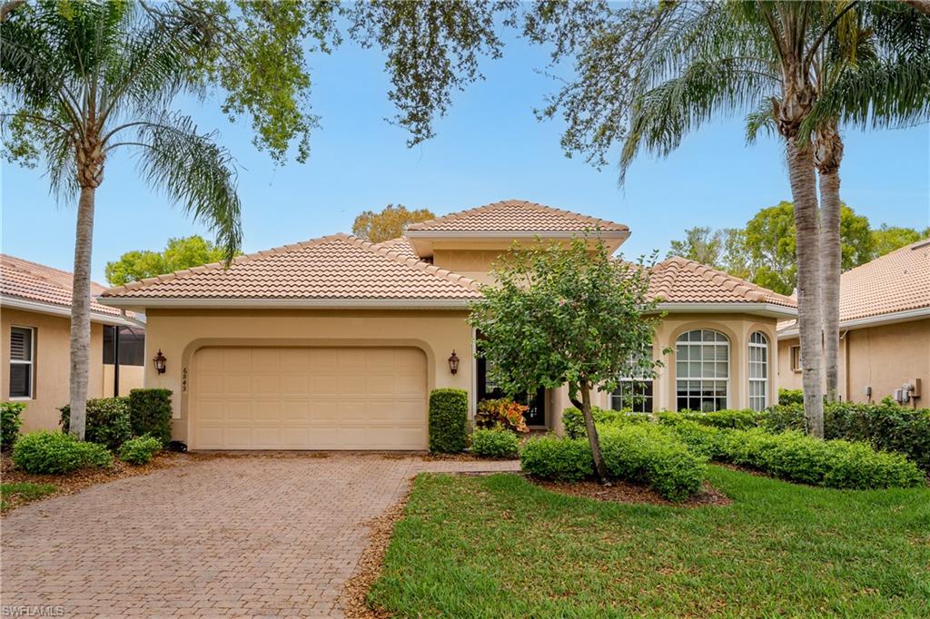 Mediterranean / spanish-style home featuring stucco siding, a garage, decorative driveway, a front yard, and a tiled roof