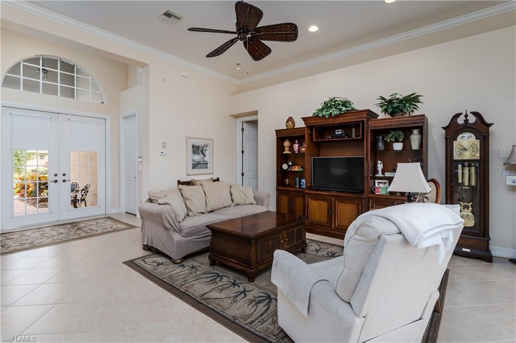 Living room featuring french doors, crown molding, a ceiling fan, and light tile patterned floors