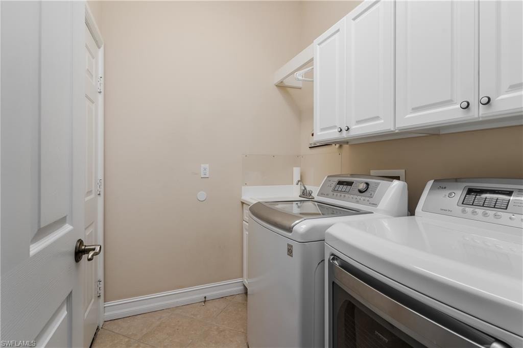Laundry area with cabinet space, washer and clothes dryer, and light tile patterned flooring