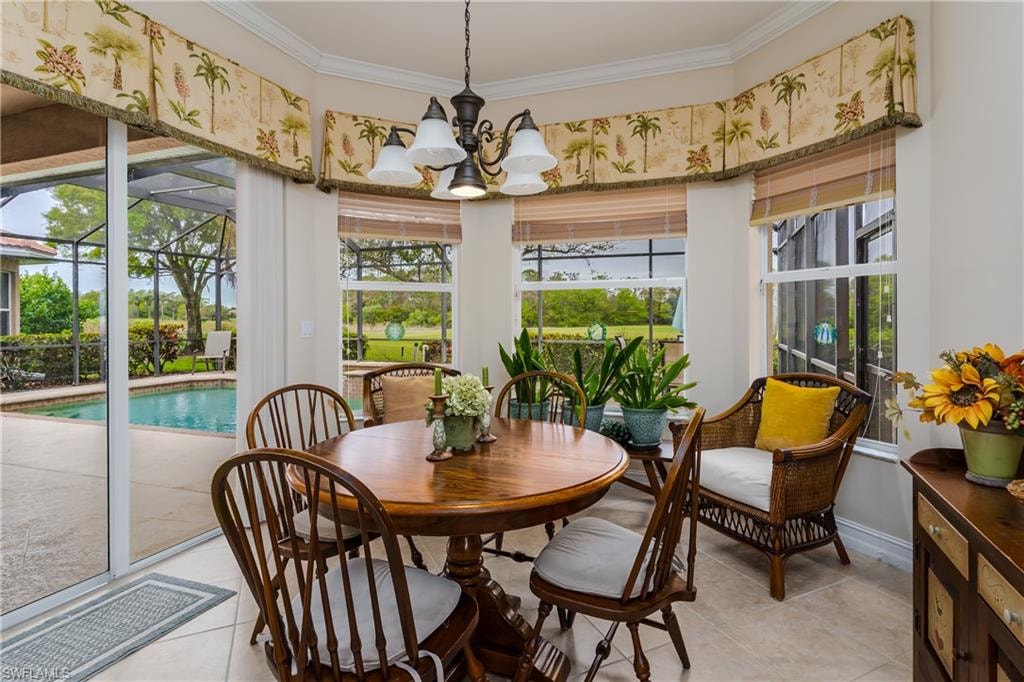 Dining space featuring a sunroom, ornamental molding, hanging lights, plenty of natural light, and light tile patterned floors