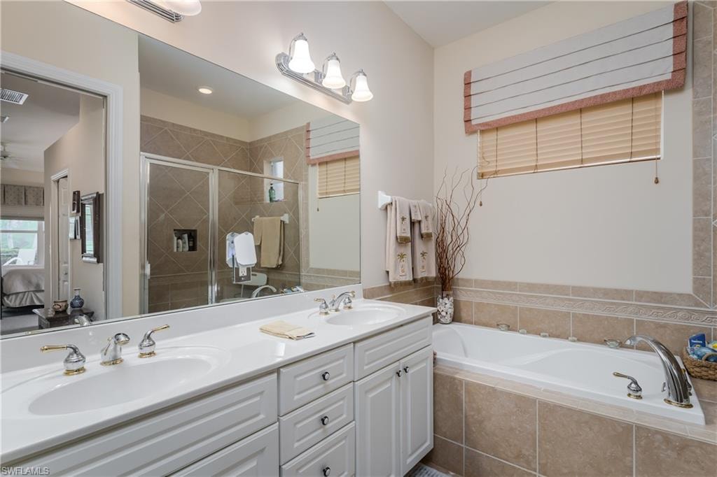 Full bathroom featuring ensuite bathroom, double vanity, a garden tub, and a stall shower
