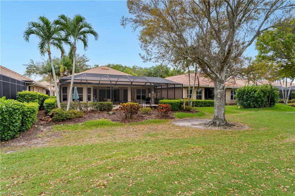 Rear view of property with a lanai, a lawn, a sunroom, and stucco siding