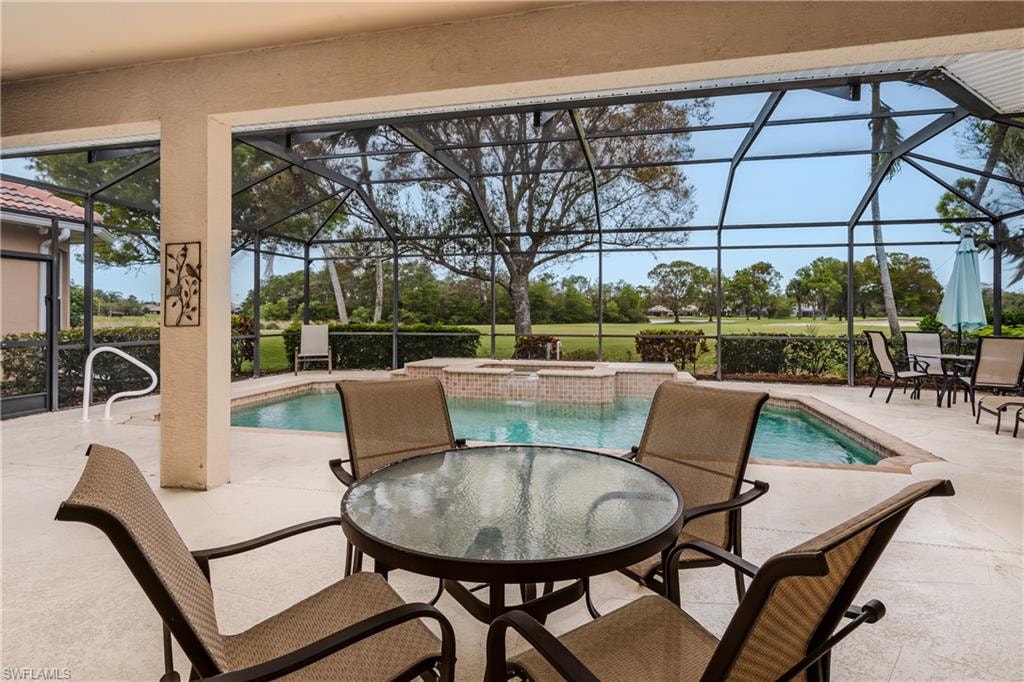 Combined pool / hot tub featuring a sunroom, a patio, outdoor dining space, and a lanai
