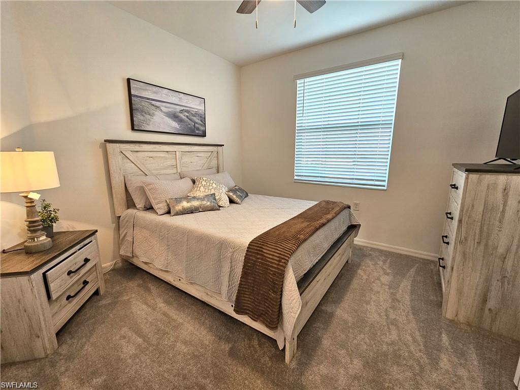 Bedroom featuring baseboards, a ceiling fan, and dark colored carpet