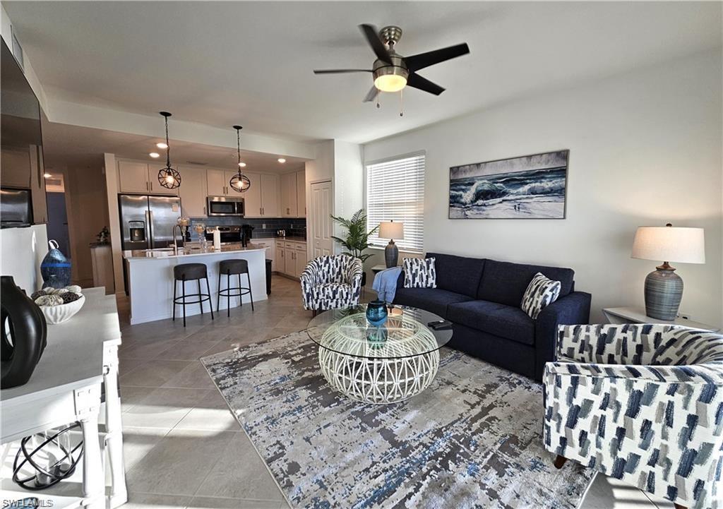 Living area featuring light tile patterned flooring and ceiling fan