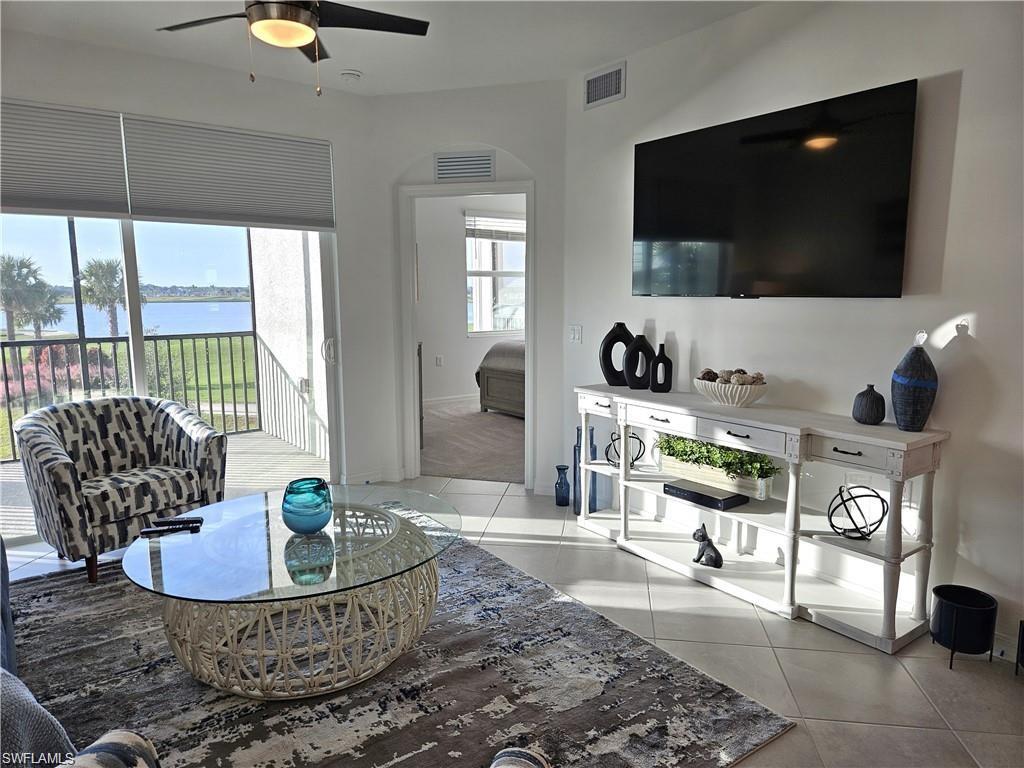 Living room featuring light tile patterned floors, ceiling fan, and visible vents