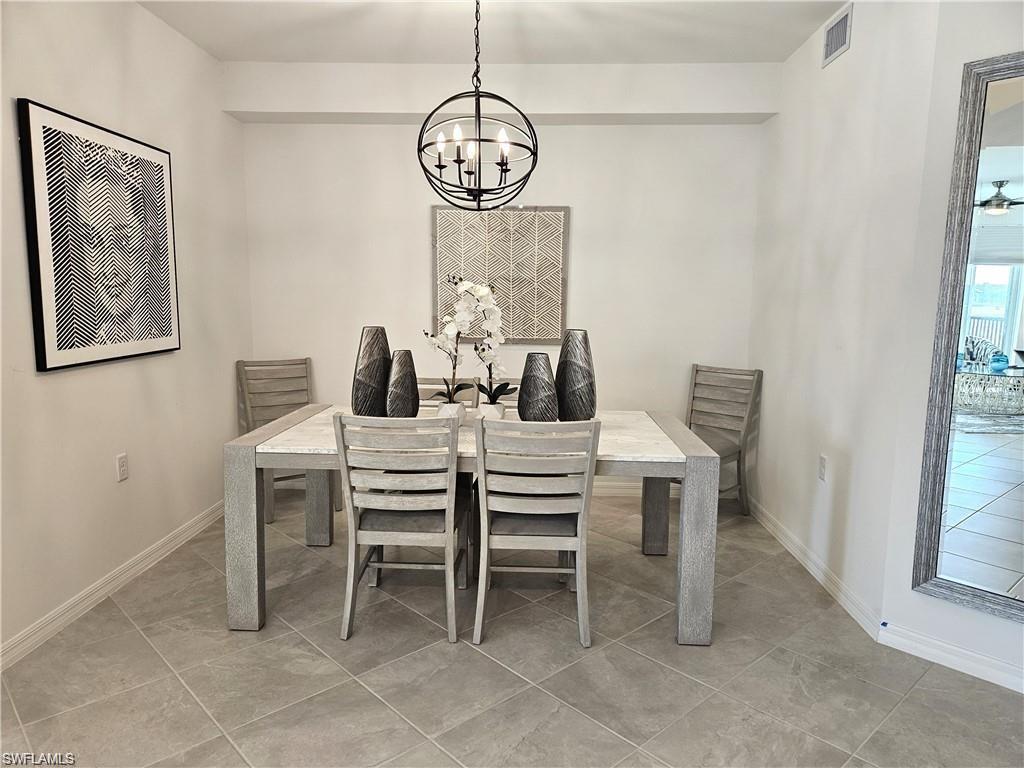 Dining room with light tile patterned floors, a notable chandelier, baseboards, and visible vents