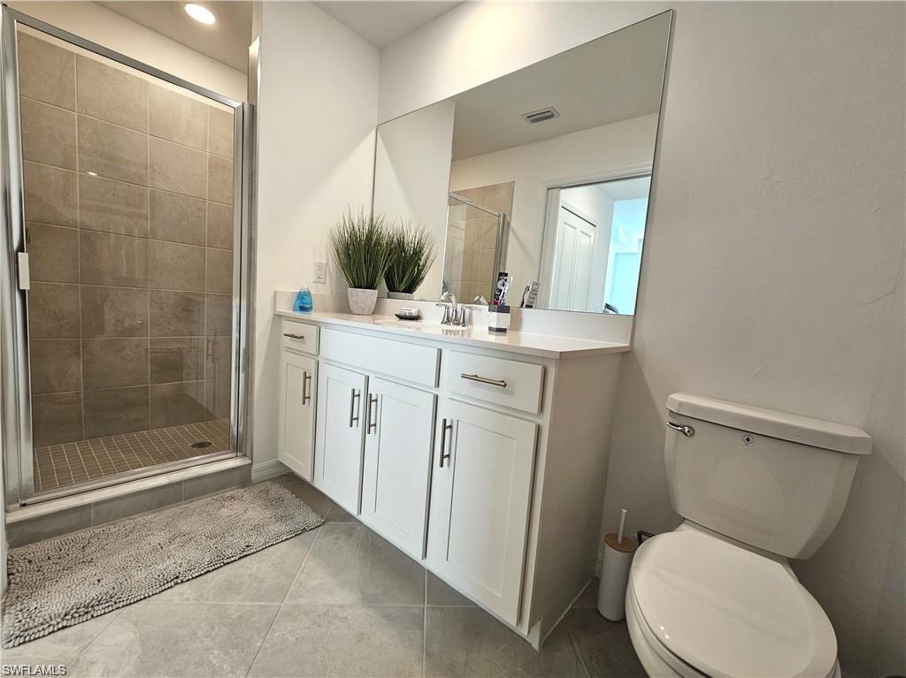 Full bath featuring vanity, toilet, a shower stall, tile patterned floors, and visible vents