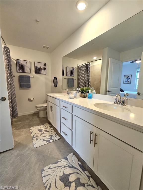 Full bath with visible vents, a sink, toilet, and double vanity