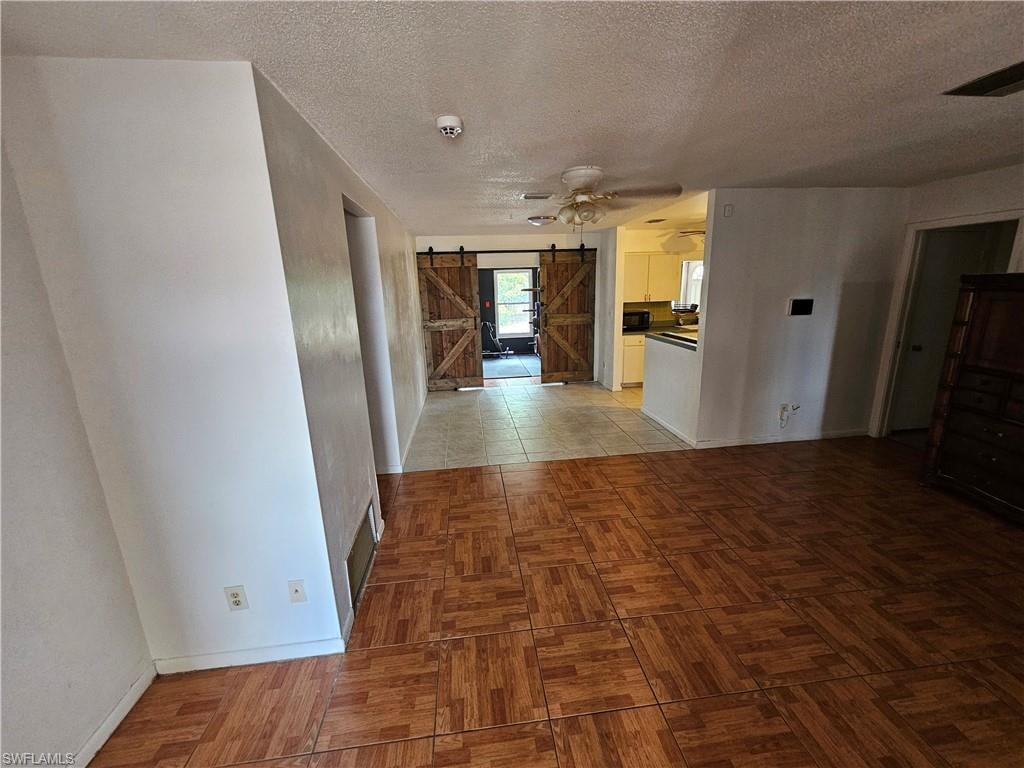 Corridor featuring a barn door, a textured ceiling, and parquet floors