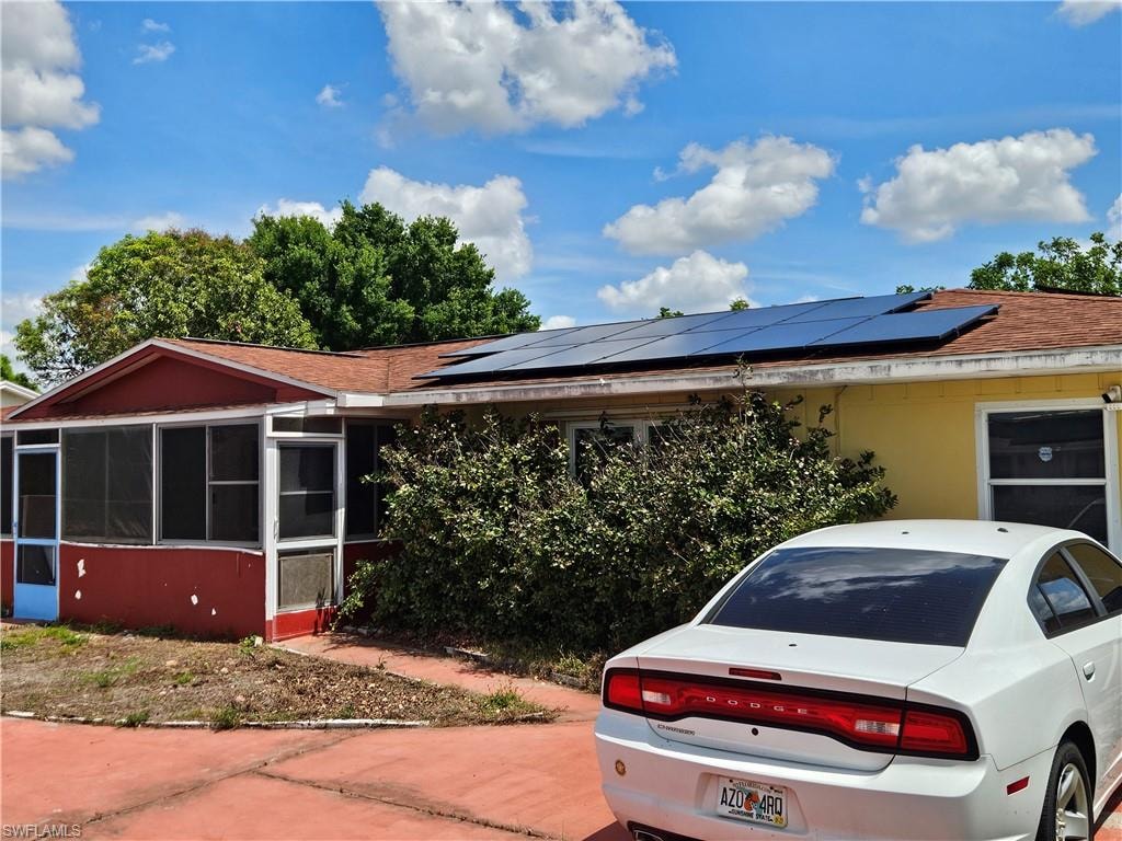 View of front of house featuring roof mounted solar panels and a sunroom