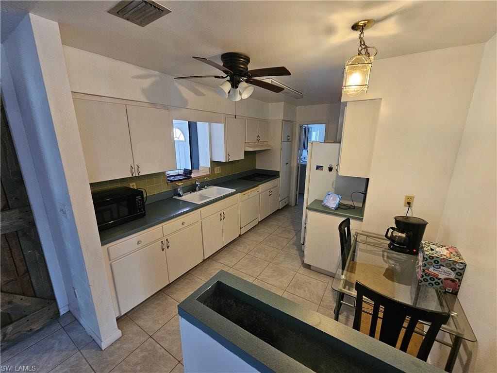 Kitchen featuring dark countertops, black appliances, backsplash, and light tile patterned floors