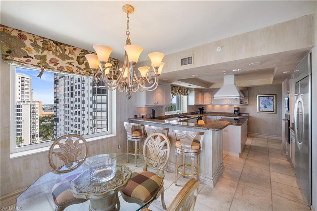 Dining room with a tray ceiling, hanging lights, and light tile patterned flooring