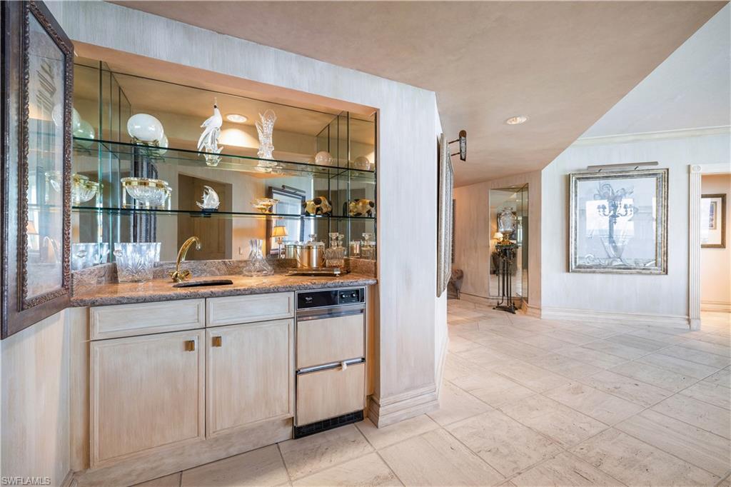 Indoor wet bar with light wood finish cabinets, light stone countertops, and recessed lighting