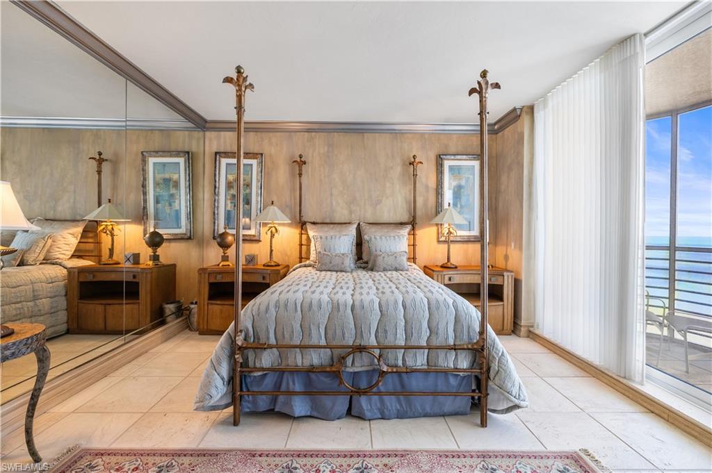 Bedroom featuring access to exterior, crown molding, multiple windows, a water view, and wooden walls