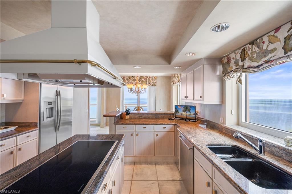 Kitchen featuring stainless steel appliances, recessed lighting, light tile patterned floors, dark stone counters, and white cabinetry