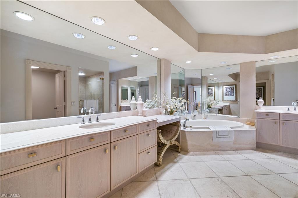 Master Bathroom featuring two vanities, a bath, recessed lighting, light tile patterned floors, and a stall shower