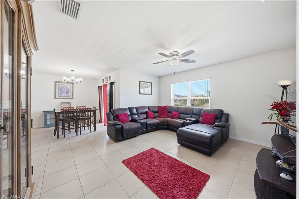 Living area featuring a ceiling fan, light tile patterned floors, and a chandelier