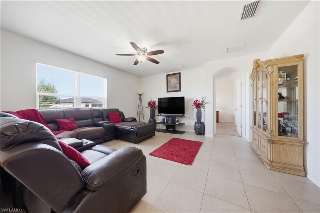 Living room featuring arched walkways, a ceiling fan, and light tile patterned flooring