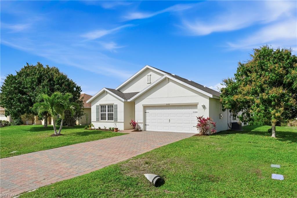 Ranch-style home with a front lawn, a garage, decorative driveway, and stucco siding