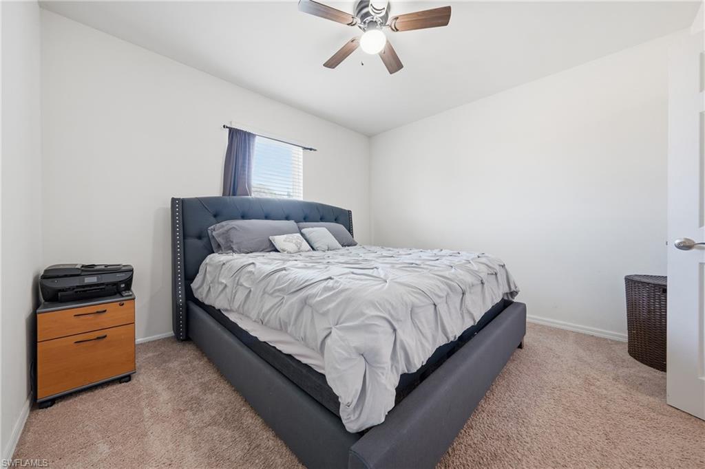 Bedroom with ceiling fan and light carpet
