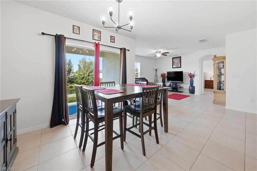 Dining space featuring hanging lights, light tile patterned flooring, a ceiling fan, and arched walkways
