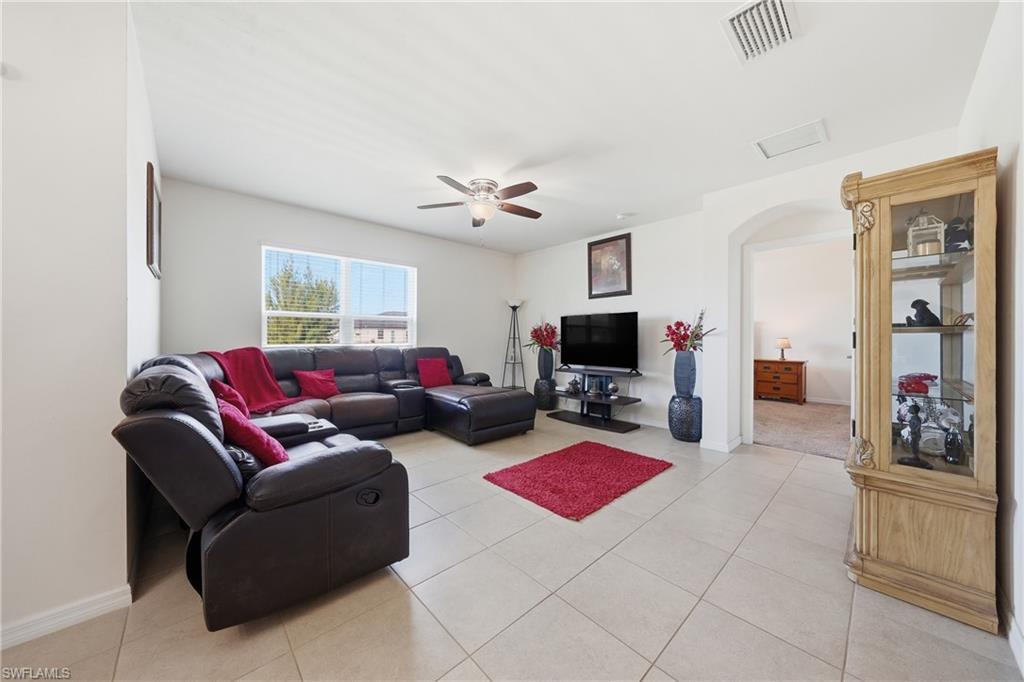 Living area with arched walkways, a ceiling fan, and light tile patterned floors