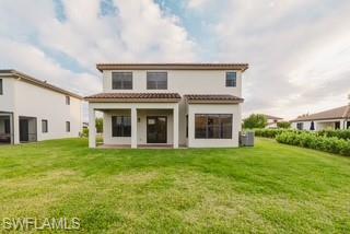 Back of property featuring a lawn, a patio area, and a tile roof